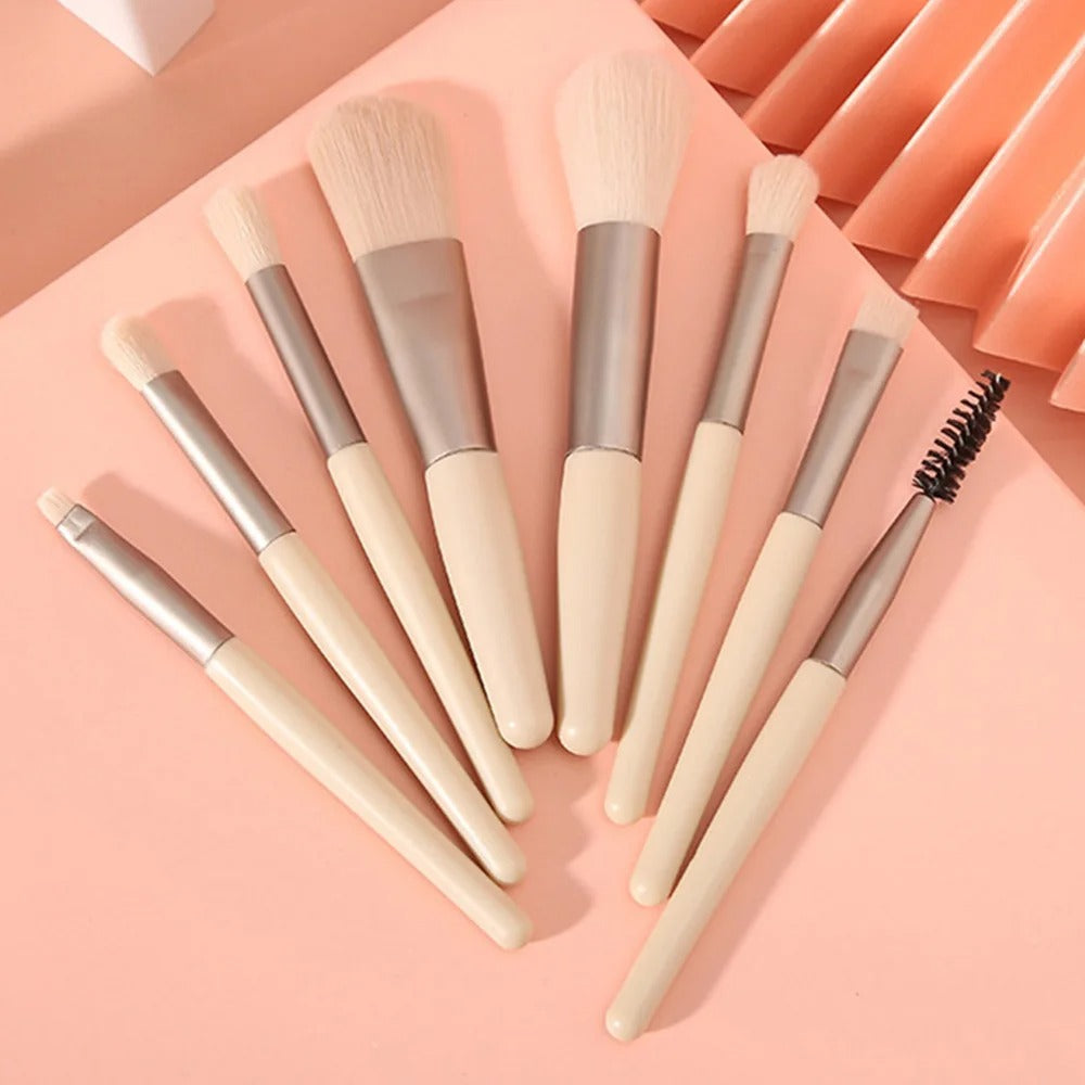 Set of makeup brushes with beige handles and brown bristles on a pink background